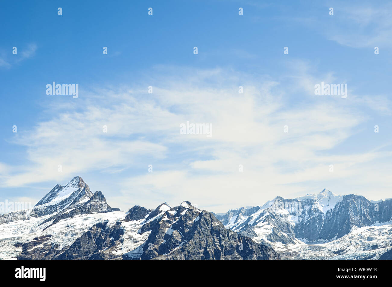 Picos de montañas alpinas con cielo azul y nubes de luz. La escalada de montaña. Copia espacio, lugar para el texto. Antecedentes motivacionales. El logro de los objetivos. Desarrollo personal. Concepto de desafío. Foto de stock