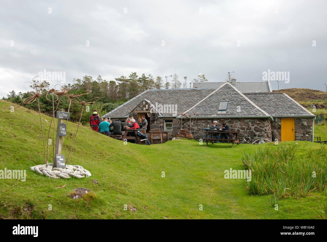 La gente de pie sentado fuera de la tienda de té Mor Puerto Isla de Muck, las pequeñas islas de Escocia a los clientes tradicionales de piedra construido isla escocesa cottag Foto de stock