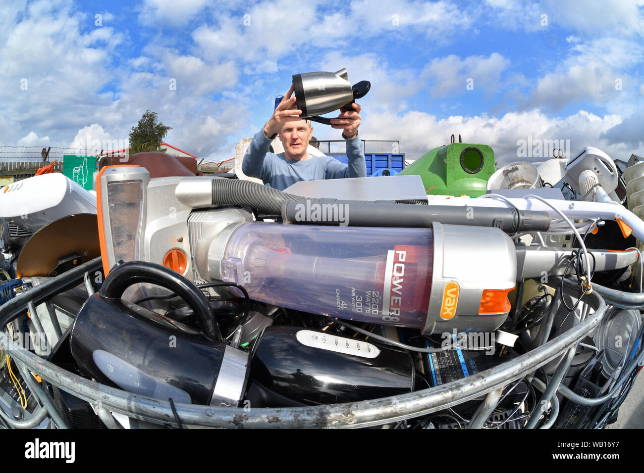 El hombre deja de aparatos eléctricos (RAEE) para reciclaje en el Consejo en el centro de reciclaje doméstico reino unido Foto de stock