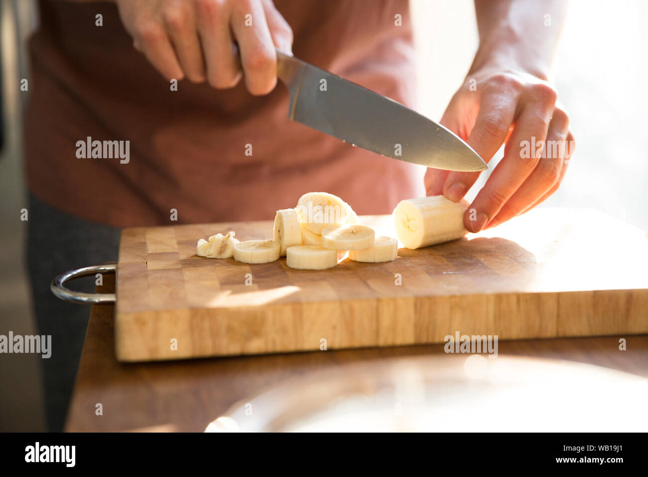 La mano del hombre picado de plátano con cuchillo de cocina Foto de stock