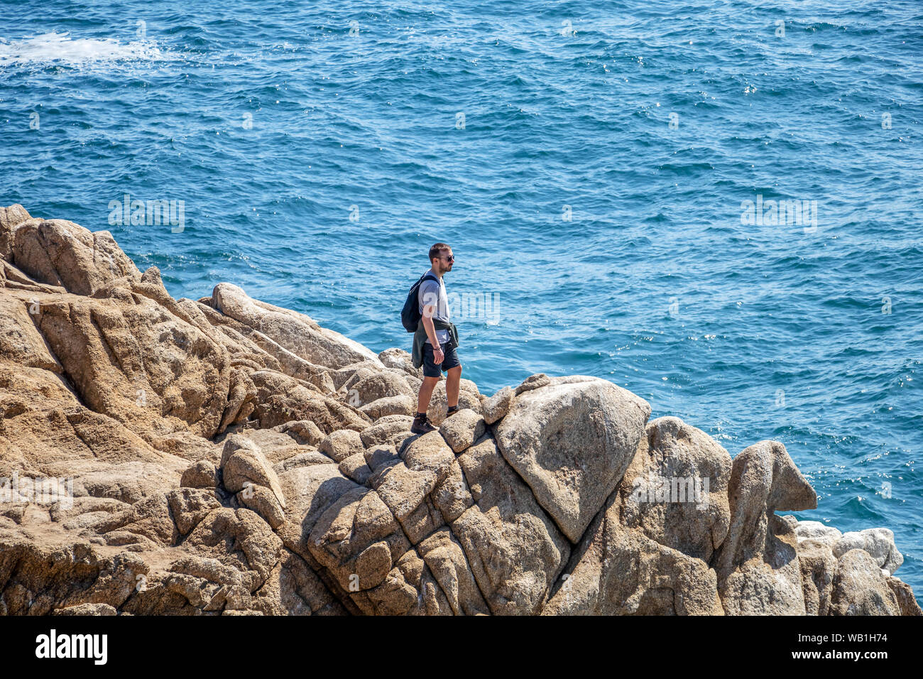 Joven valiente caminante de pie en la rocosa costa del Océano Pacífico Foto de stock
