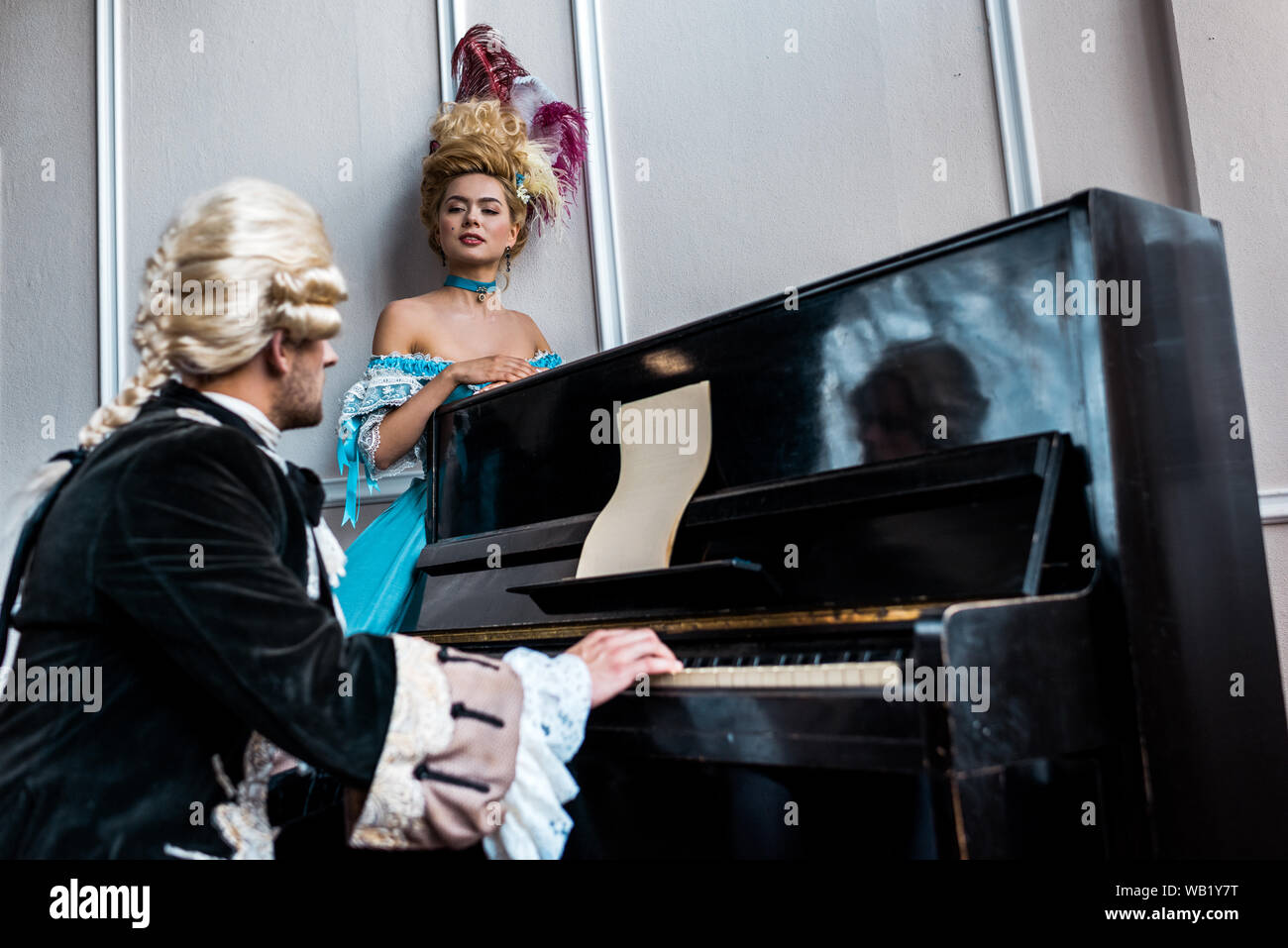 El enfoque selectivo victoriano de una mujer mirando al hombre en la peluca  tocando el piano Fotografía de stock - Alamy