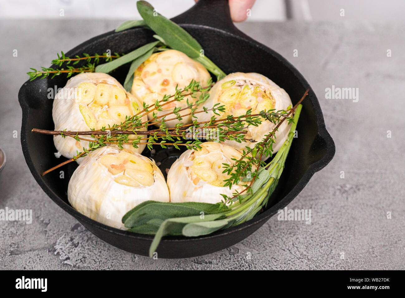 Cabezas de ajo crudo con especias frescas en sartén de hierro fundido para  preparar recetas de ajo asado Fotografía de stock - Alamy