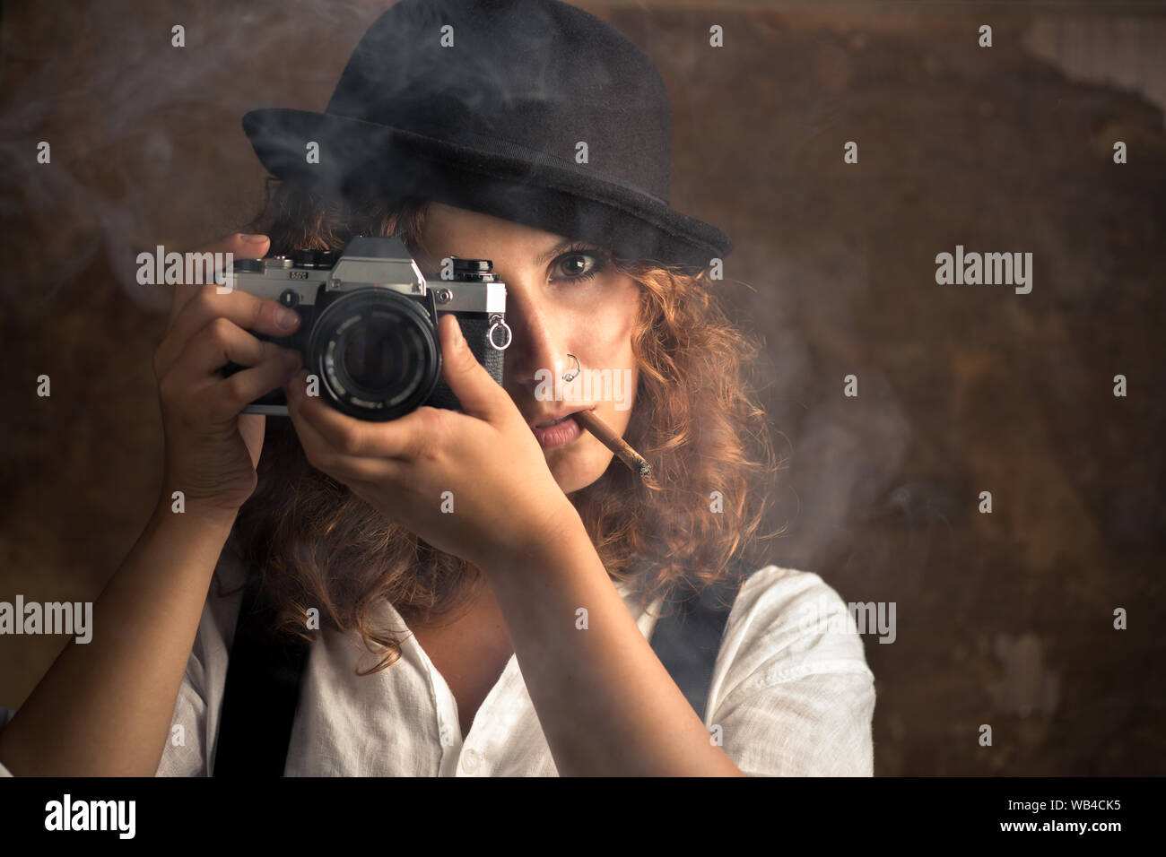 Mujer fotógrafo con Bowler y tirantes fumar un cigarro Foto de stock