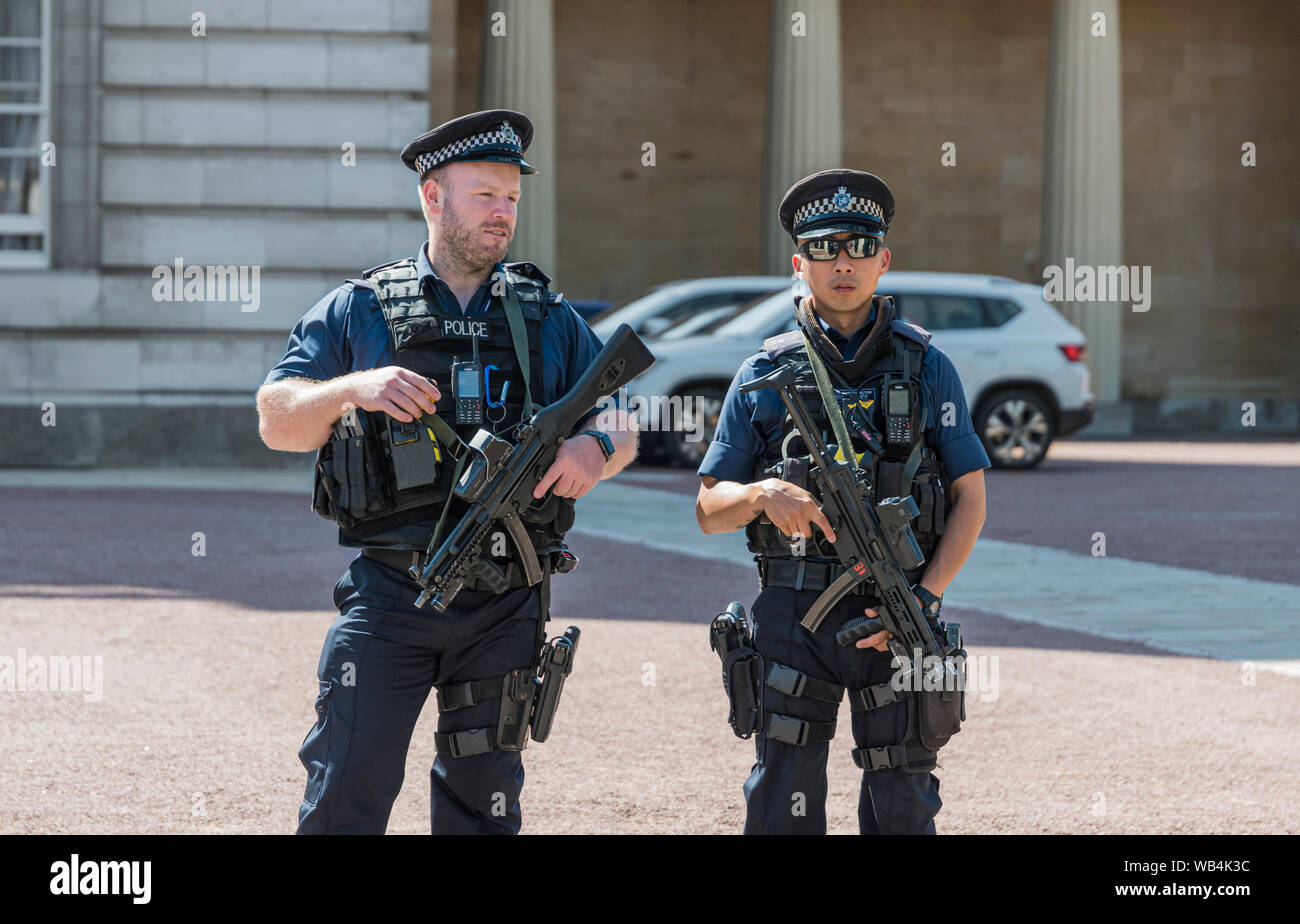 Par de policías metropolitanos armados portando armas fuera del Palacio de Buckingham en la ciudad de Westminster, en el centro de Londres, Inglaterra, Reino Unido. Foto de stock