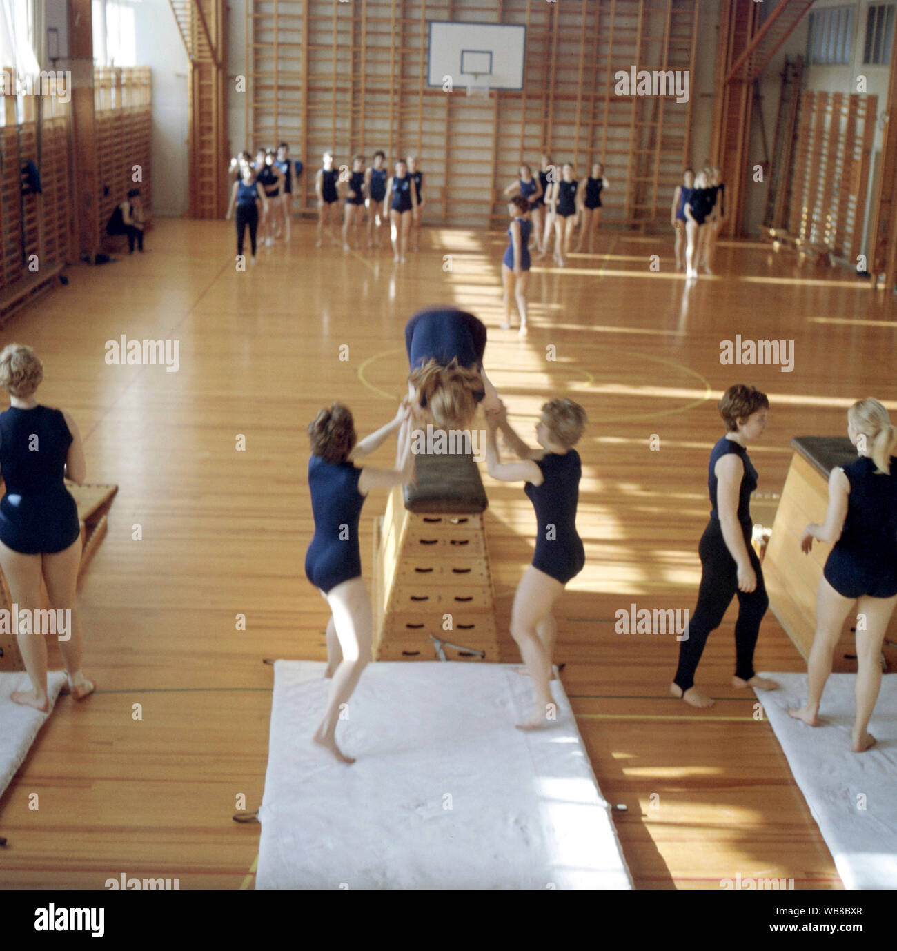 La escuela de la gimnasia en la década de 1960. Un maestro en una escuela gimnasio está celebrando una lección y los estudiantes escuchan a sus instrucciones. Suecia 1960 Foto de stock