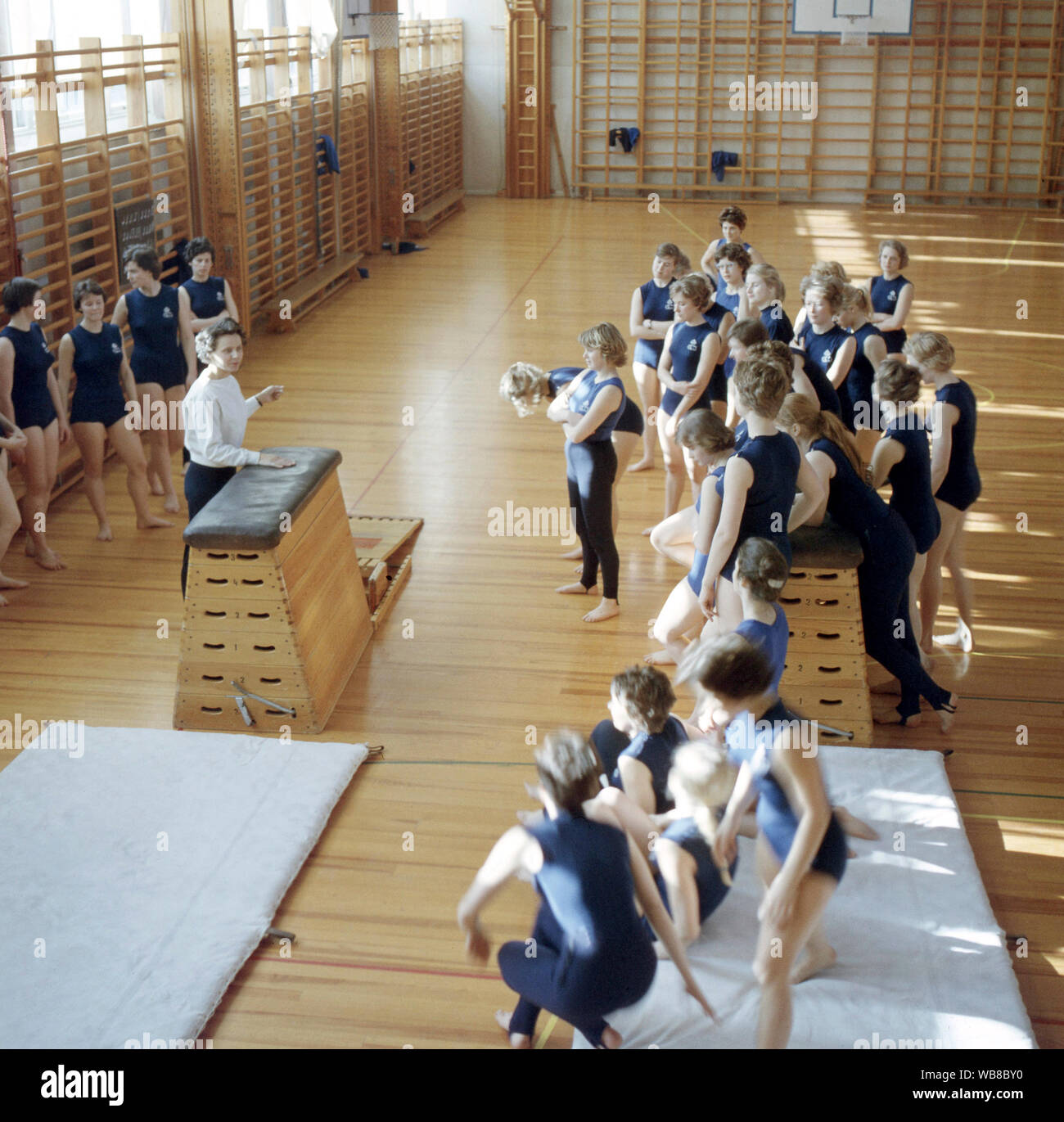 La escuela de la gimnasia en la década de 1960. Un maestro en una escuela gimnasio está celebrando una lección y los estudiantes escuchan a sus instrucciones. Suecia 1960 Foto de stock
