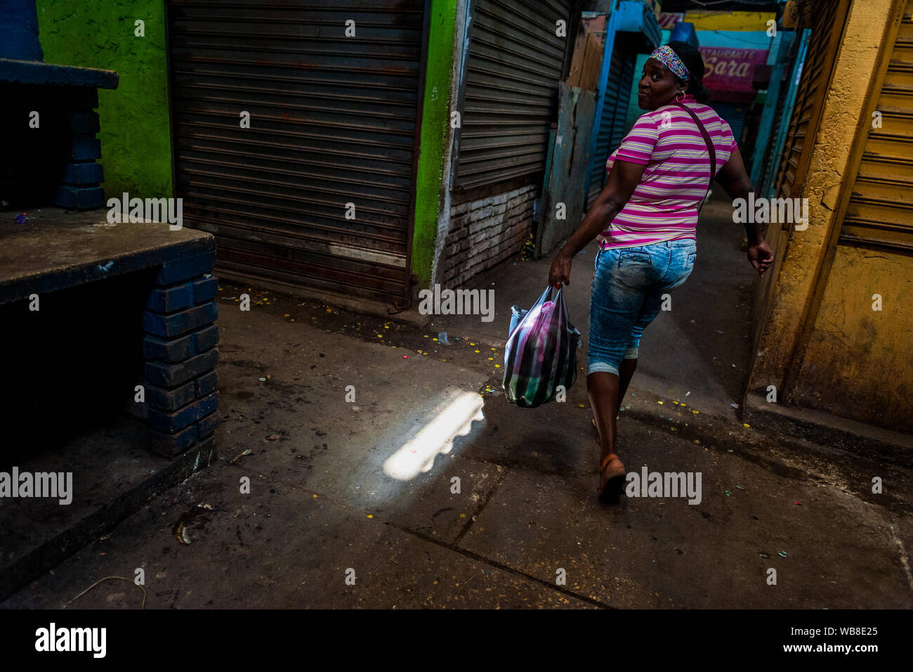 Una mujer Afrocolombiana, llevar hortalizas compradas en la bolsa de plástico, paseos dentro del mercado de Bazurto en Cartagena, Colombia. Foto de stock