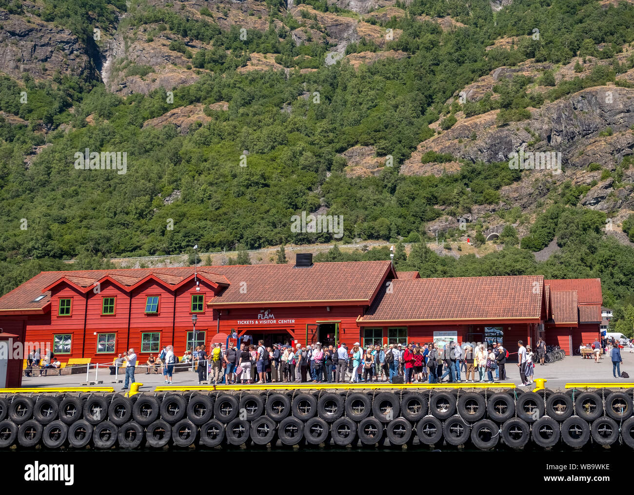 Flåm, turistas en entradas & Visitor Center, casa de madera roja, amarres para barcos, rocas, árboles, Sogn og Fjordane, Noruega, Escandinavia, Europa, ni Foto de stock