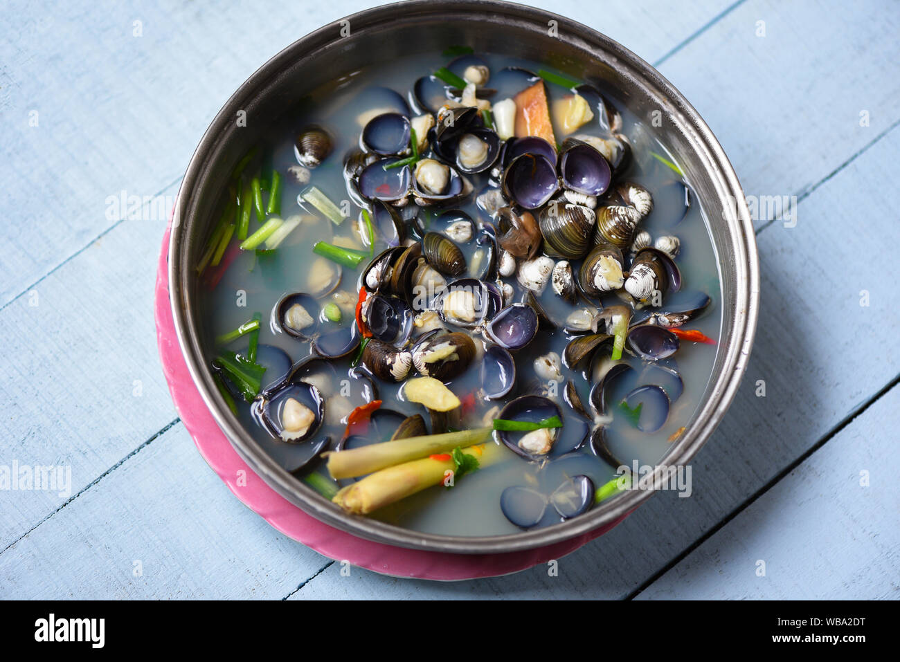 Shijimi marisco bivalvo de agua dulce tales como las almejas shell cocinados con hierbas y especias en el tazón de sopa sobre la mesa de madera Foto de stock