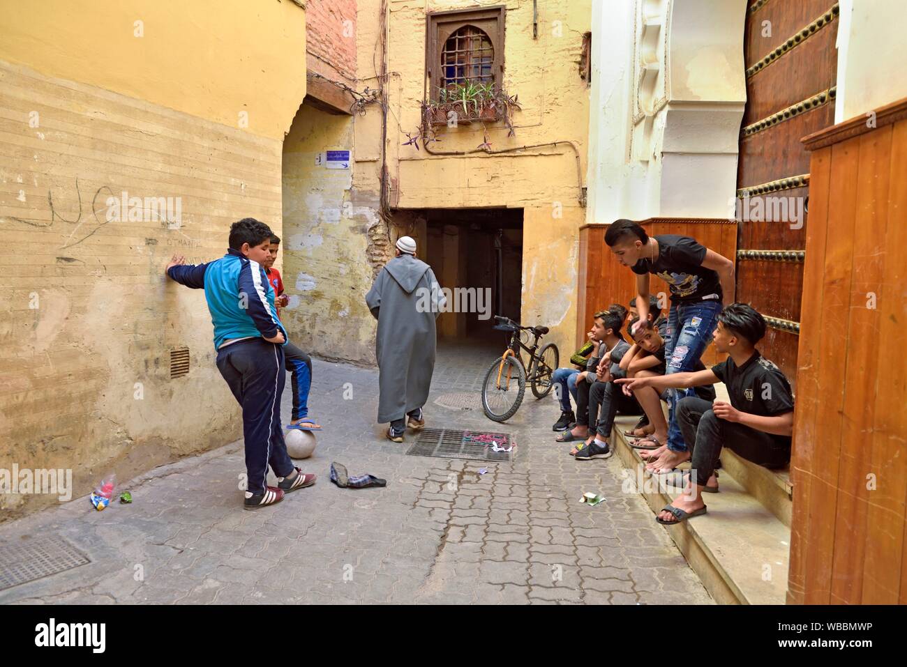Los jóvenes jugando en una angosta calle de la Medina de Marrakech, Marruecos, Norte de África Occidental. Foto de stock