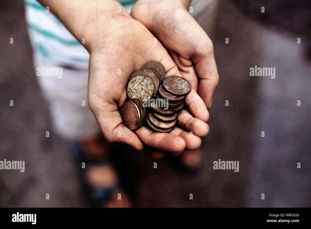 Niño sosteniendo puñado de monedas descubiertas con un detector de metales. Foto de stock