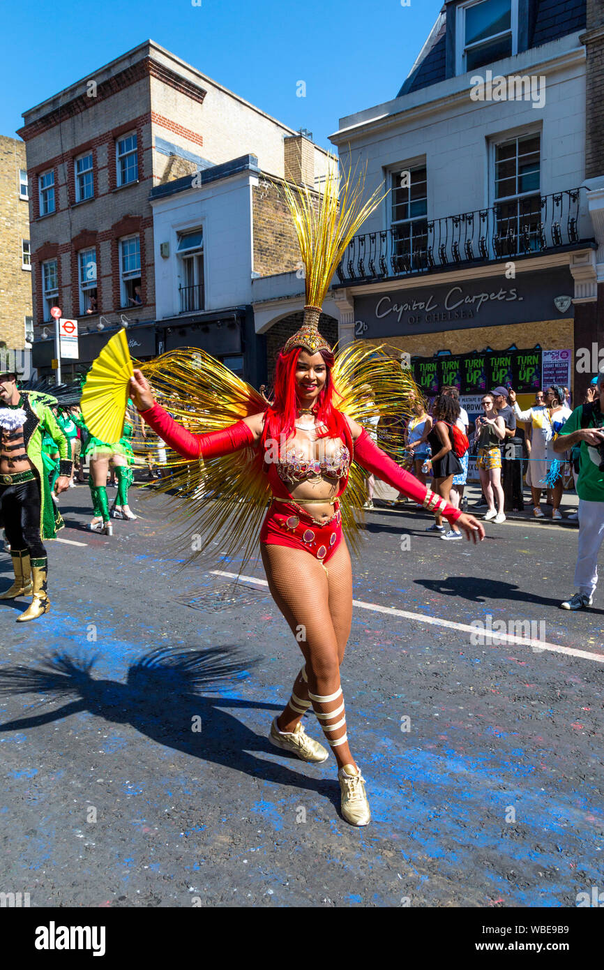 26 Agosto 2019 - bailarín de samba vistiendo un traje rojo y dorado con alas plegables y el Carnaval de Notting Hill de ventilador en un caluroso día festivo Lunes, Londres, Reino Unido. Foto de stock
