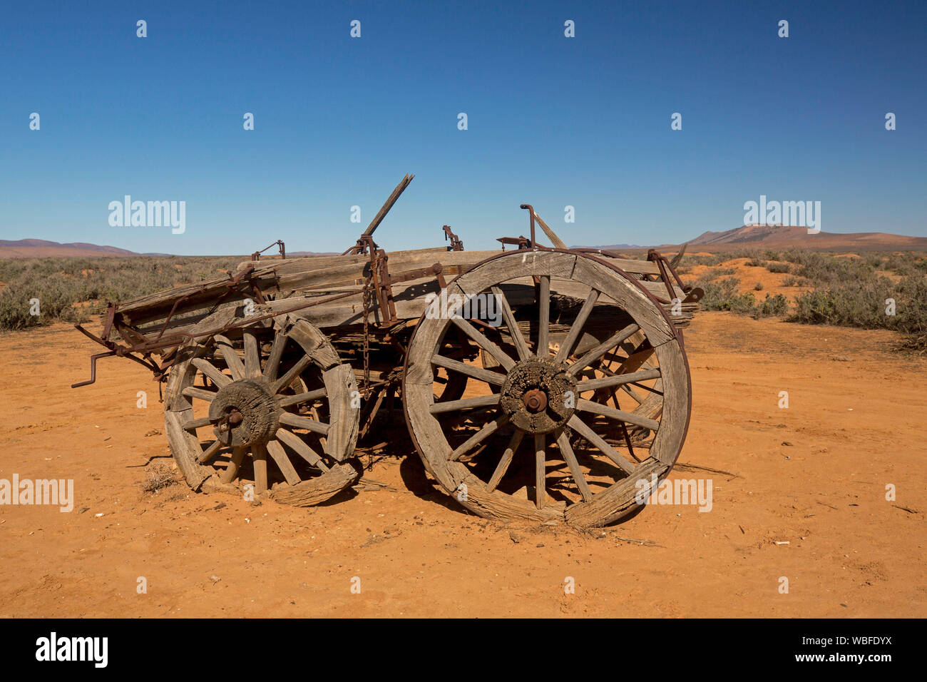 Granja de caballos viejo vagón abandonado en remoto y árido paisaje outback con suelo rojo y vegetación baja en llanuras bajo un cielo azul, en el sur de Australia Foto de stock