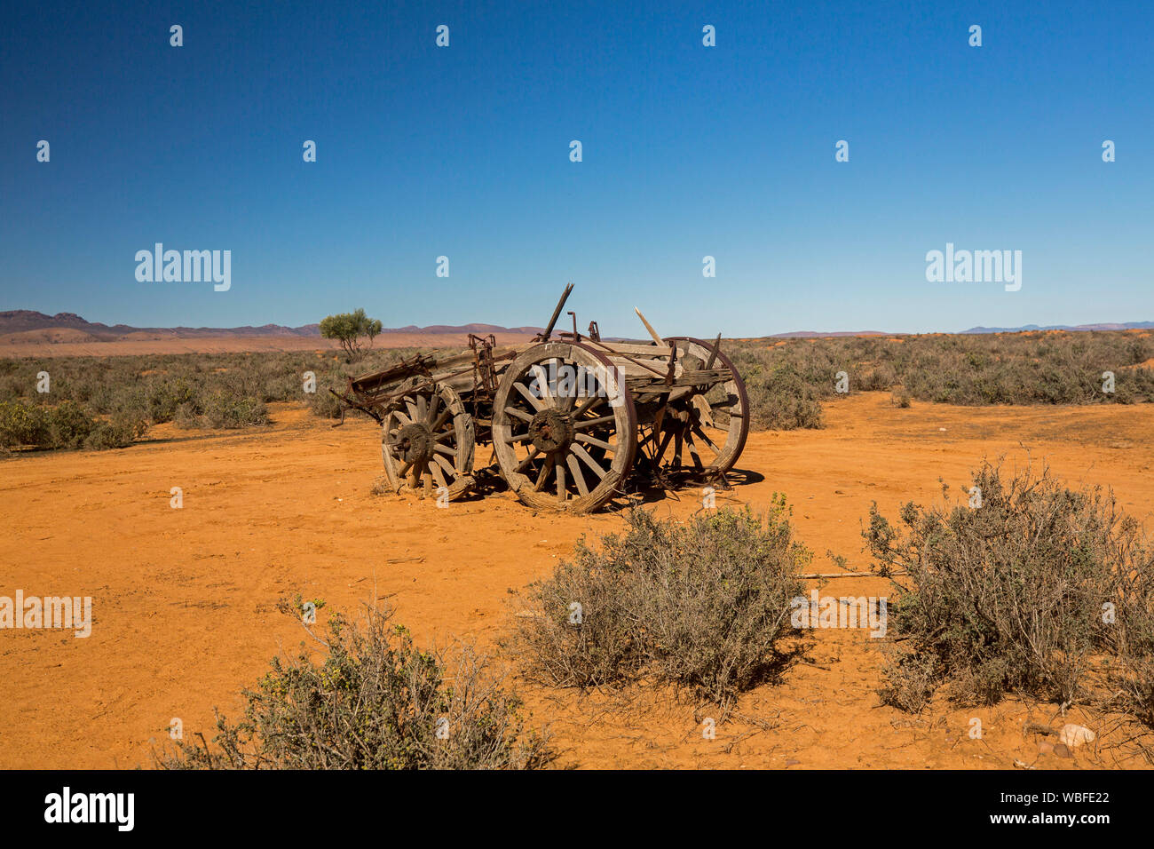 Granja de caballos viejo vagón abandonado en remoto y árido paisaje outback con suelo rojo y vegetación baja en llanuras bajo un cielo azul, en el sur de Australia Foto de stock