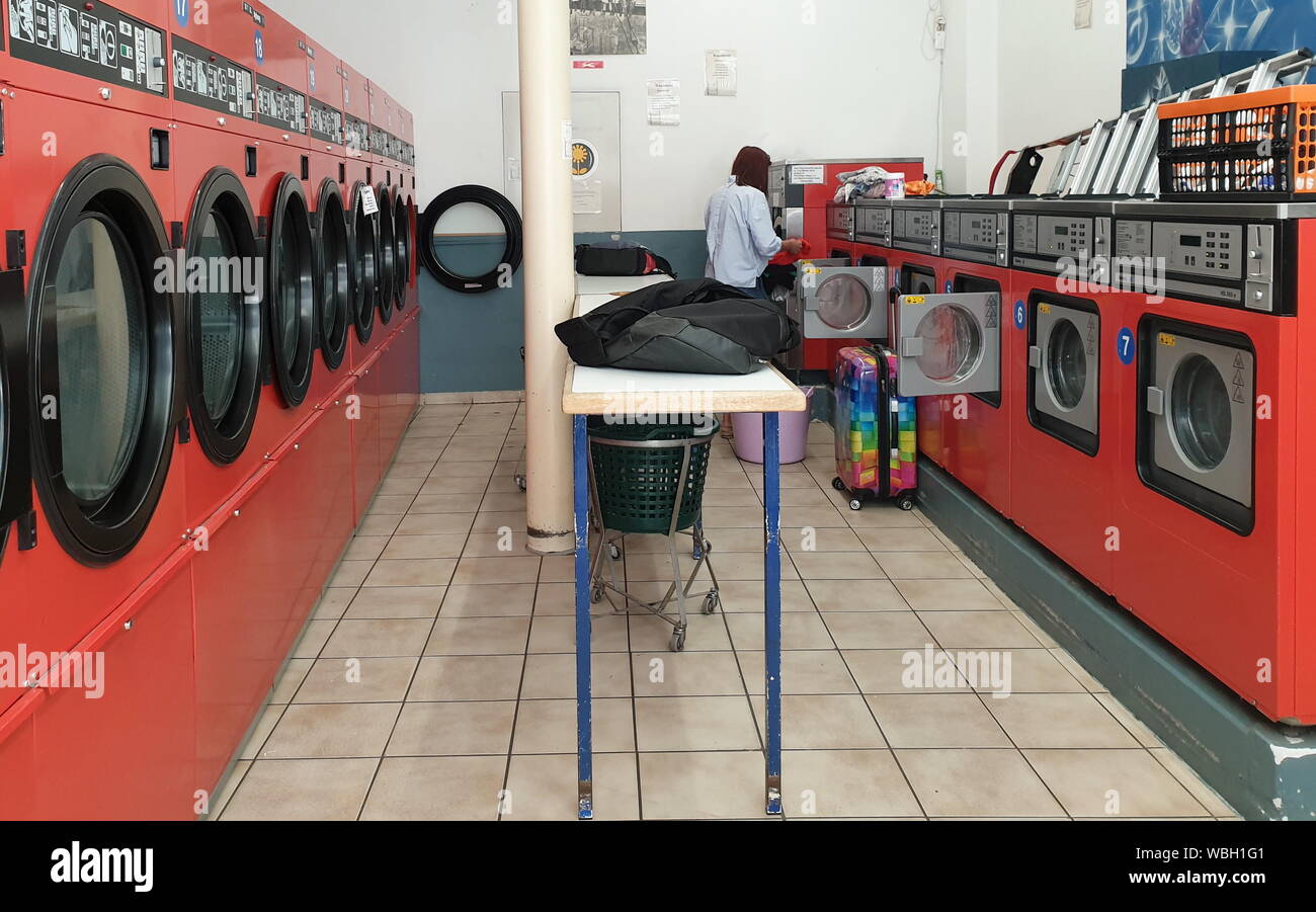 21 de agosto de 2019, Hesse, Marburg: una mujer llena de una máquina con la ropa en la lavandería "Waschbrett'. Ponga la ropa en poner en la moneda: Aunque la mayoría