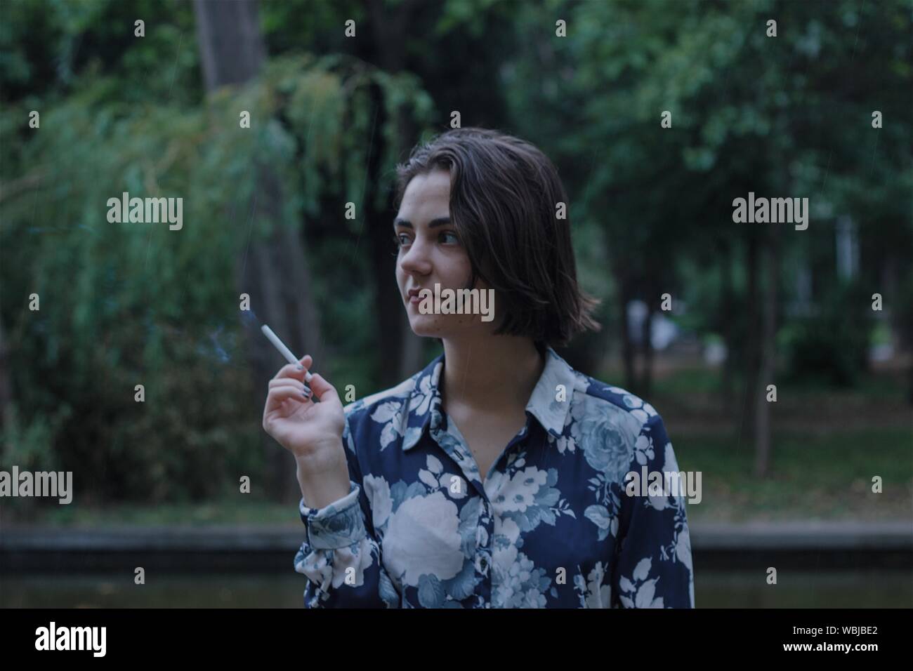 Close-up de reflexivo Adolescente fumar cigarrillo contra árboles Foto de stock