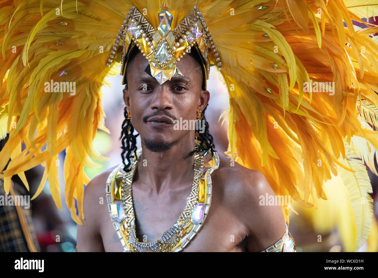 Un hombre vestido con un traje de cabeza de plumas amarillas en el Carnaval  de Notting Hill Fotografía de stock - Alamy