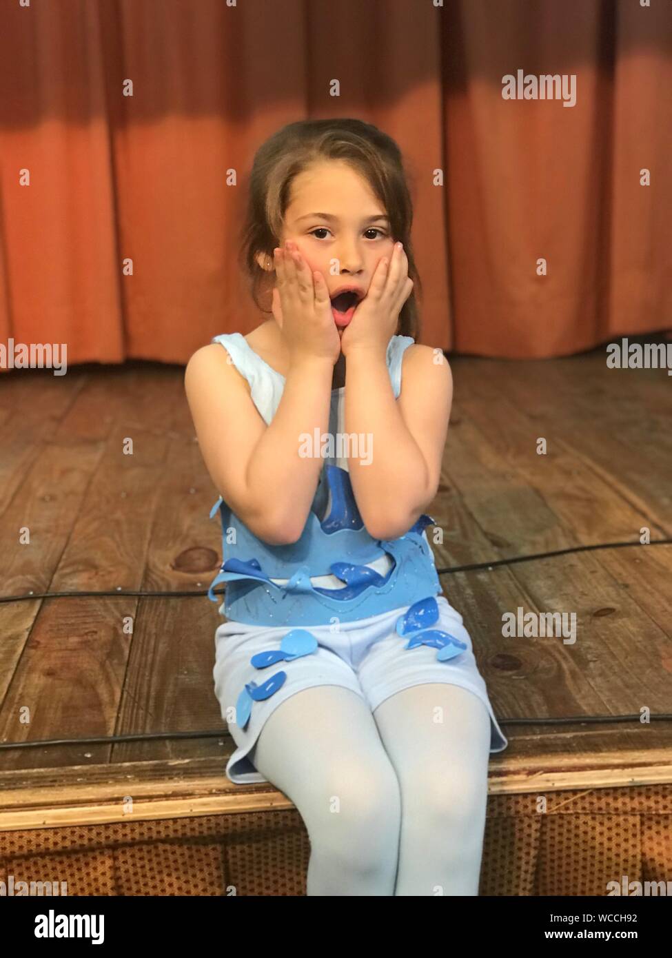 Retrato de conmocionado chica sentada en el escenario Foto de stock