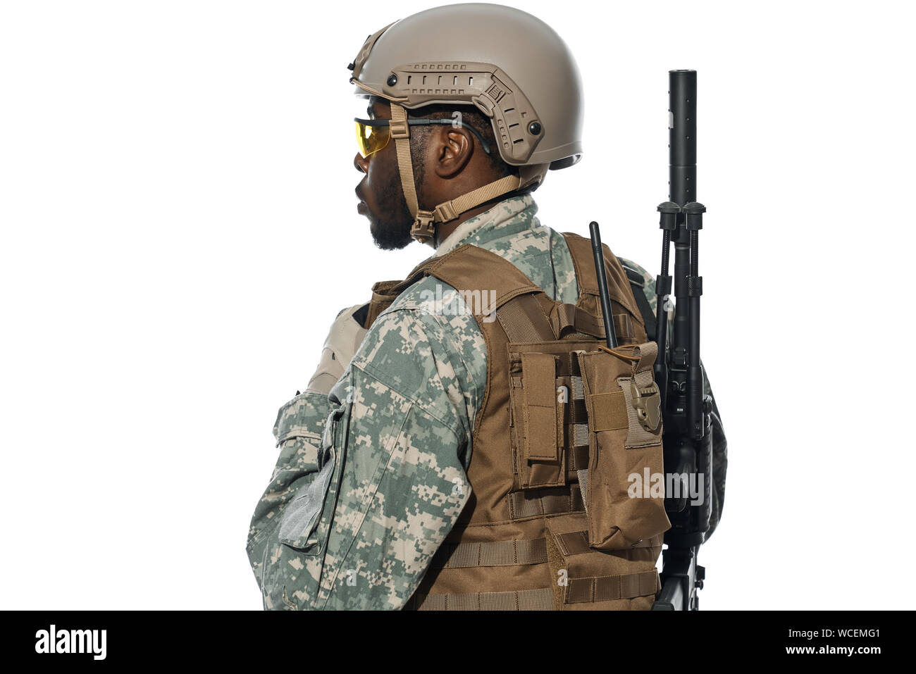 Vista posterior del soldado profesional con mochila y la instalación de una  radio para comunicación remota. Macho americano del ejército vestidos de  uniforme y casco mirando a la distancia. Antecedentes aislados en