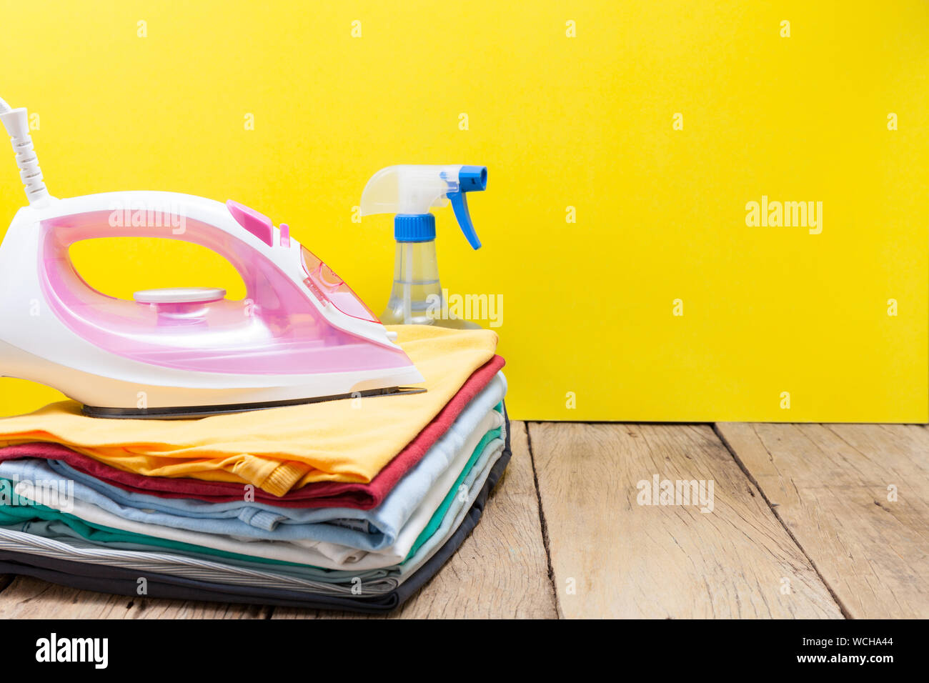 Cerca de plegado de ropa con plancha sobre mesa de madera contra el fondo  amarillo Fotografía de stock - Alamy