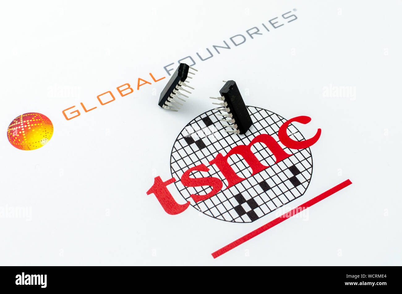 Fundiciones global vs. TSMC. Imprimir logotipos de empresas de semiconductores y dos chips, uno para atacar y otro para defender su posición. Fotografía conceptual. Foto de stock