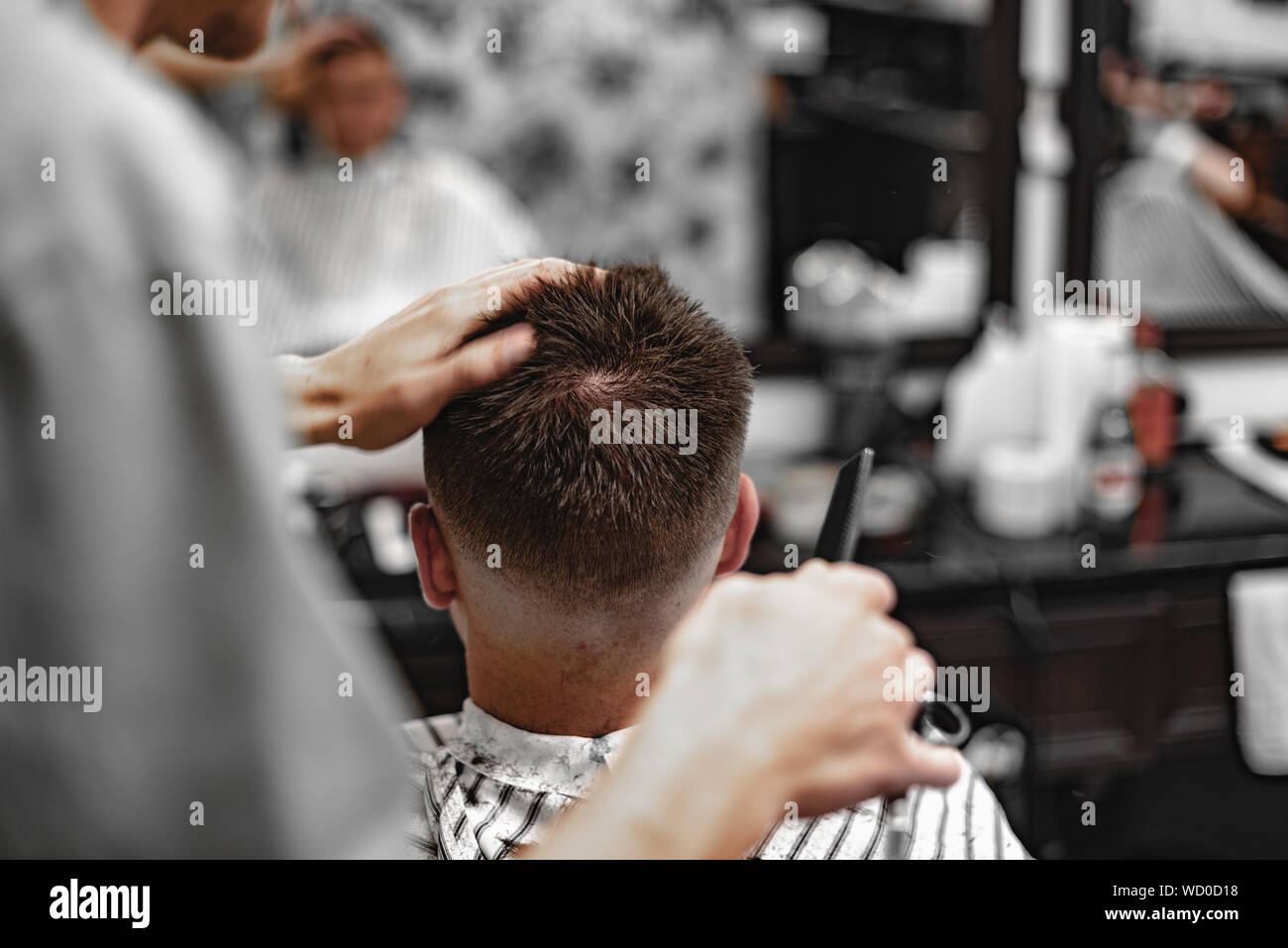 Un barbero usa cortadoras de oro para cortar la barba de un hombre en una  barbería