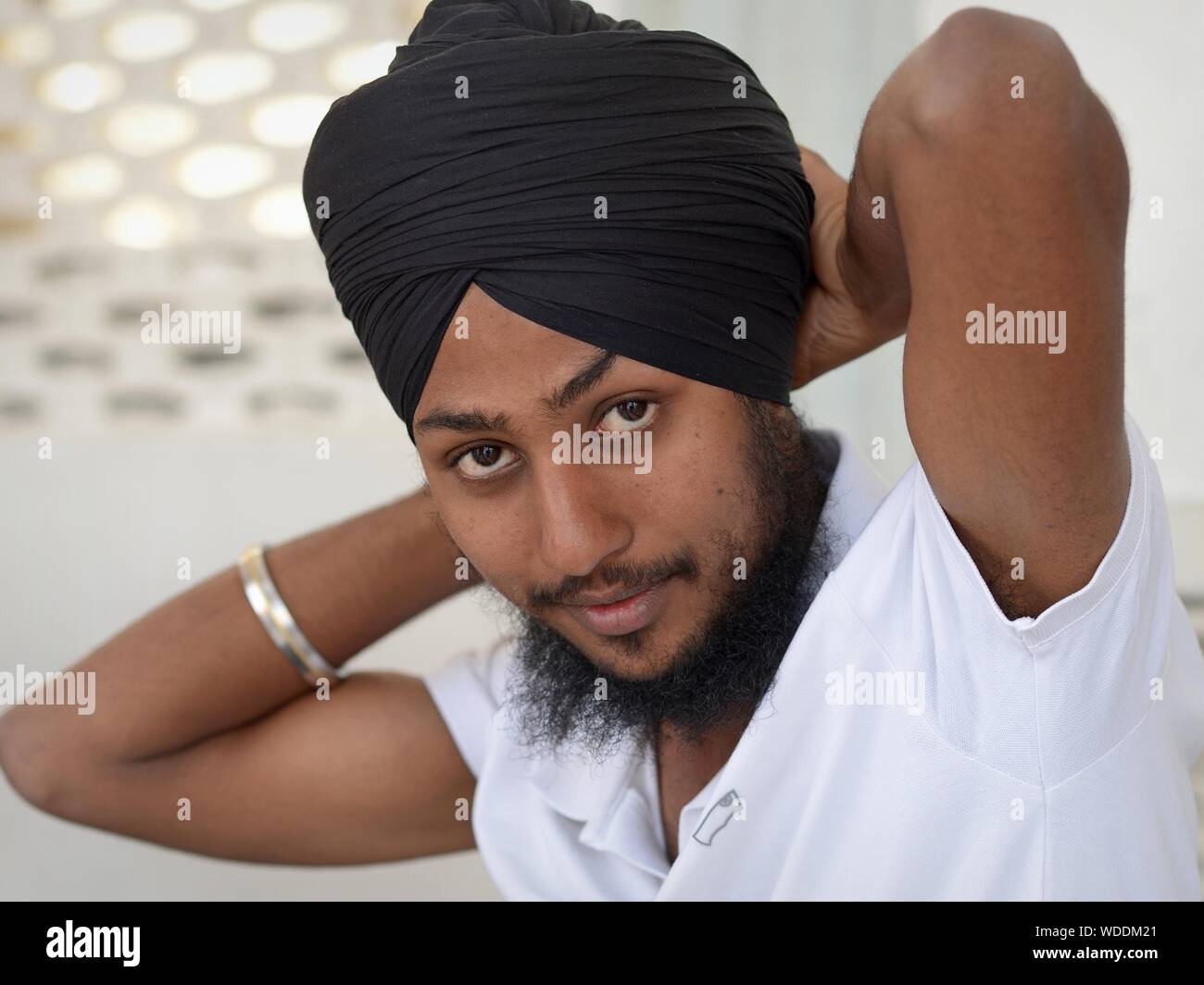 Los jóvenes de la India devoto Sikh une su tradicional turbante Sikh (dastar) y mira a la cámara. Foto de stock