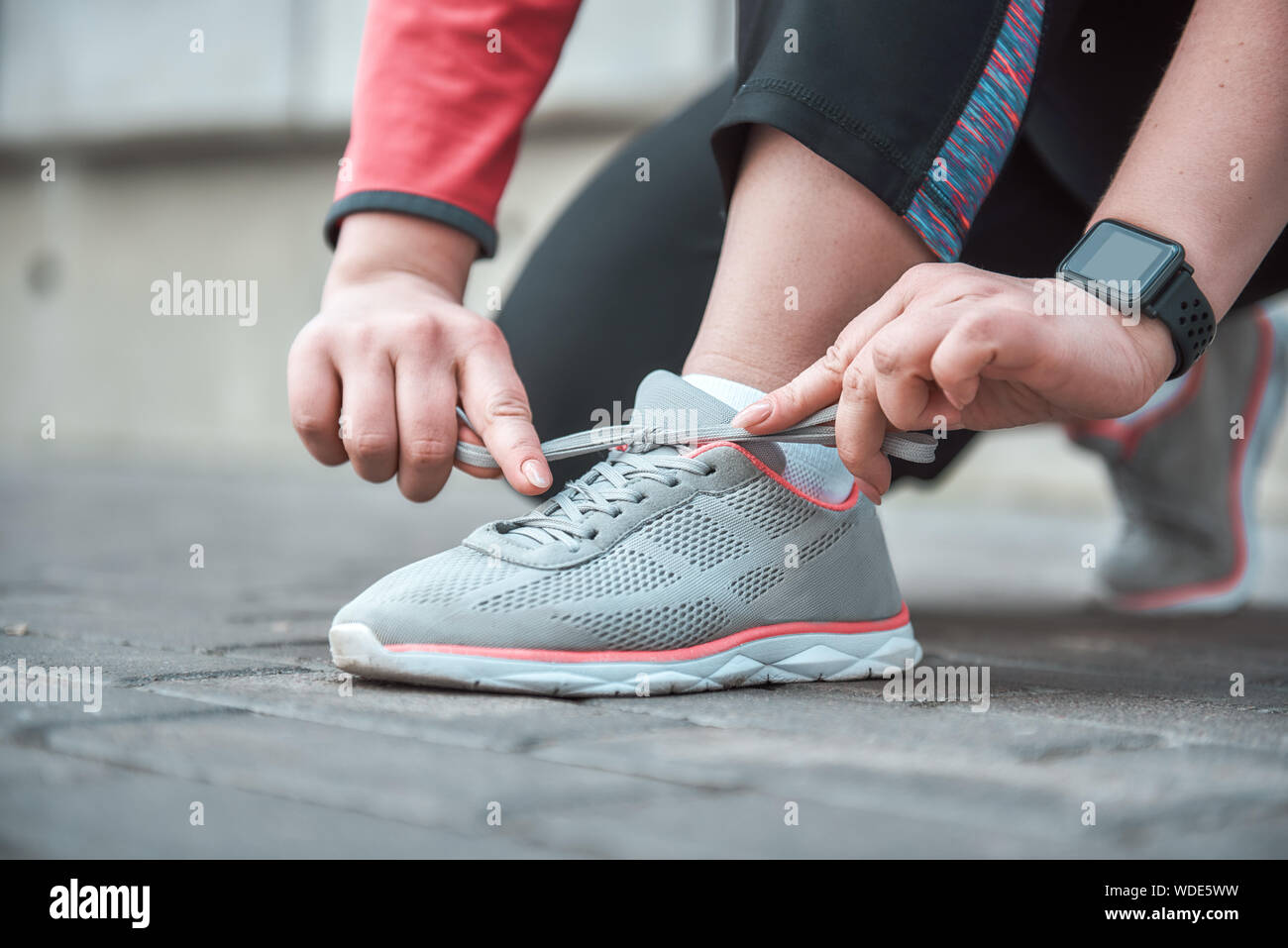 Imagen recortada de una mujer en ropa deportiva shoelace atado mientras está parado afuera. Concepto de deporte Foto de stock