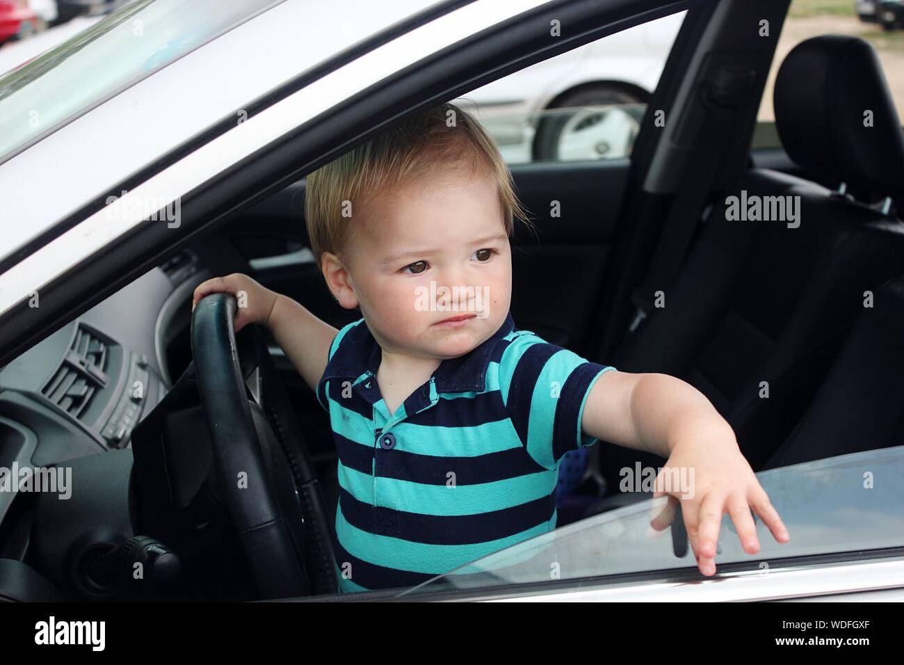 Baby Boy mirando a otro lado mientras está sentado en el asiento del conductor en el coche Foto de stock