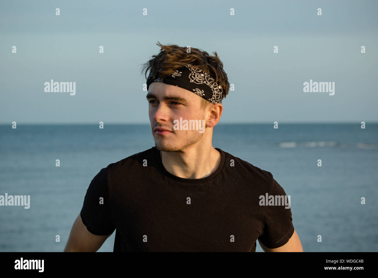 Macho adulto joven retrato en hora dorada en la playa Foto de stock