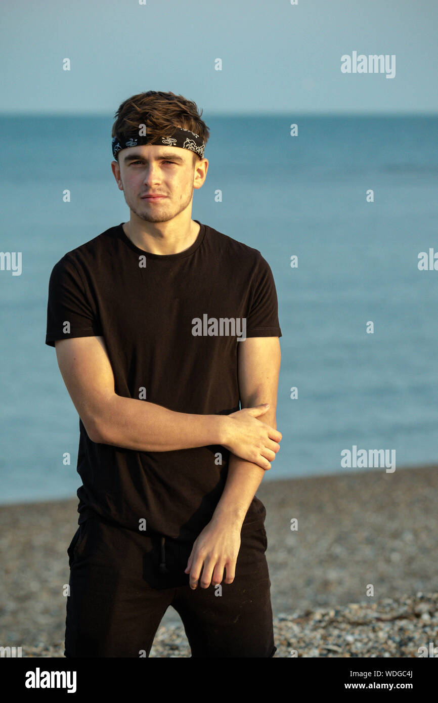 Macho adulto joven retrato en hora dorada en la playa Foto de stock