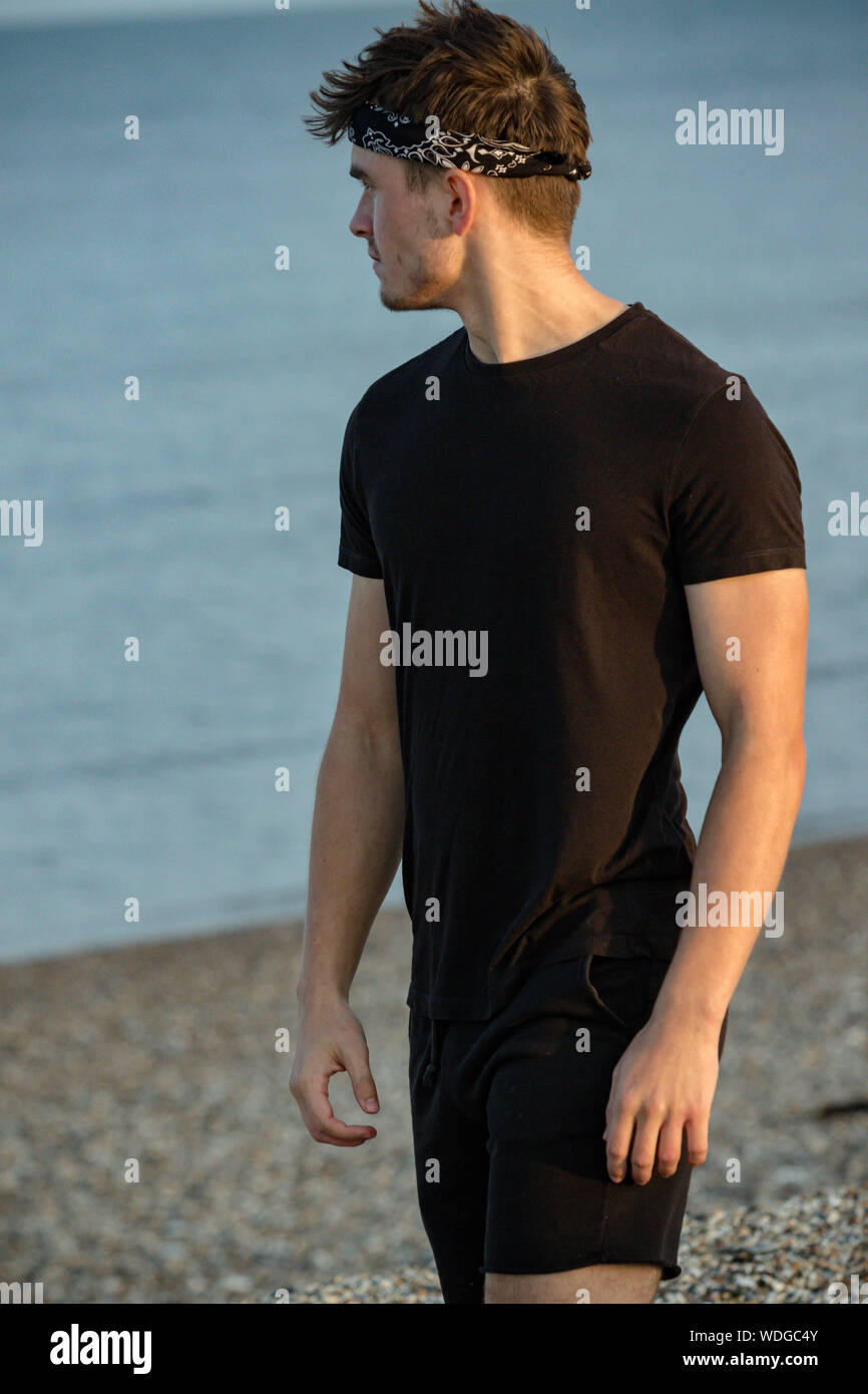 Macho adulto joven retrato en hora dorada en la playa Foto de stock