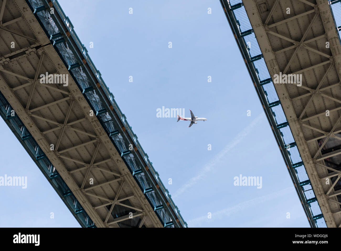 Vista del Tower Bridge apoya con un chorro plano colocado entre ellos contra un cielo azul. Foto de stock