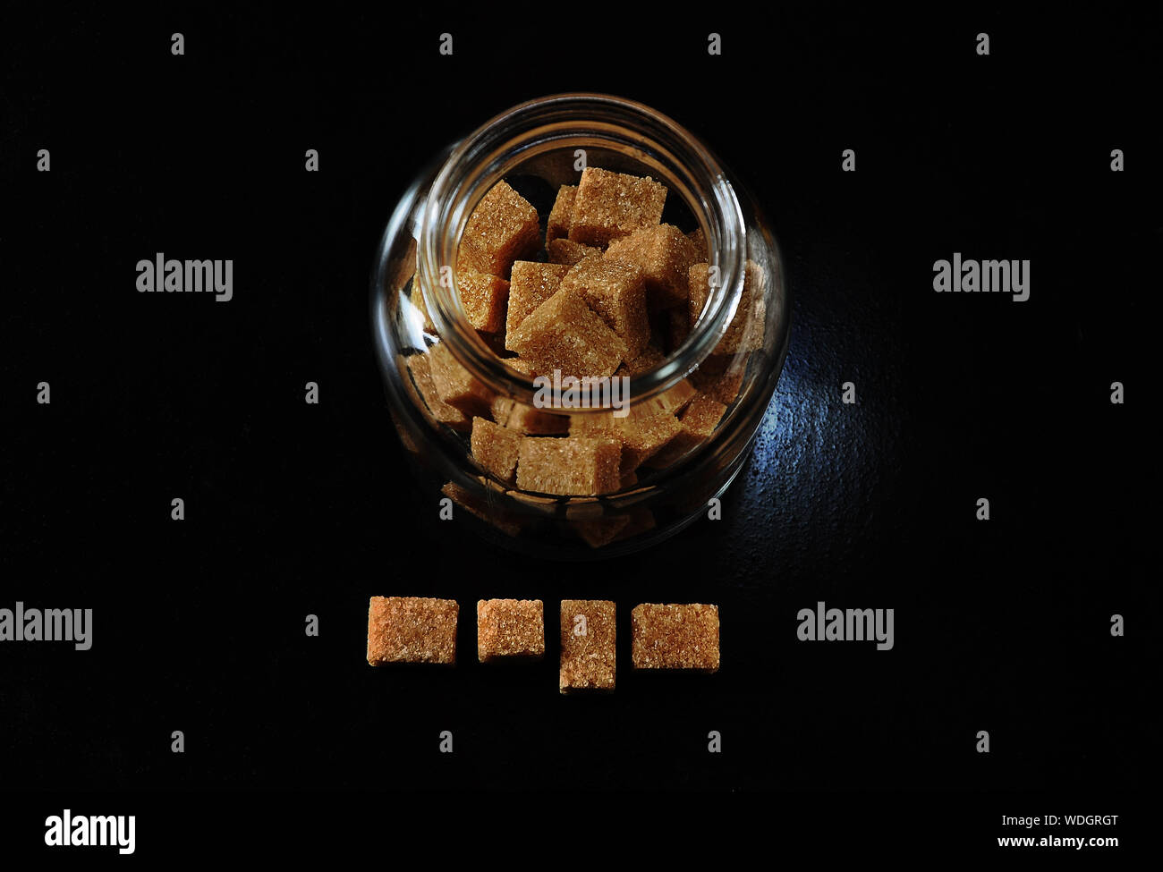 Cubos de azúcar marrón con jarra de cristal en la mesa Foto de stock