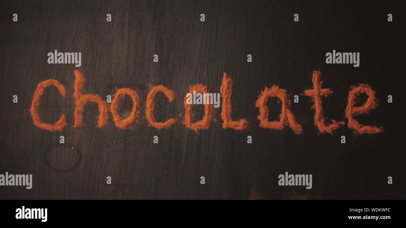 Inscripción el chocolate por cacao en polvo sobre un fondo negro grafito Foto de stock
