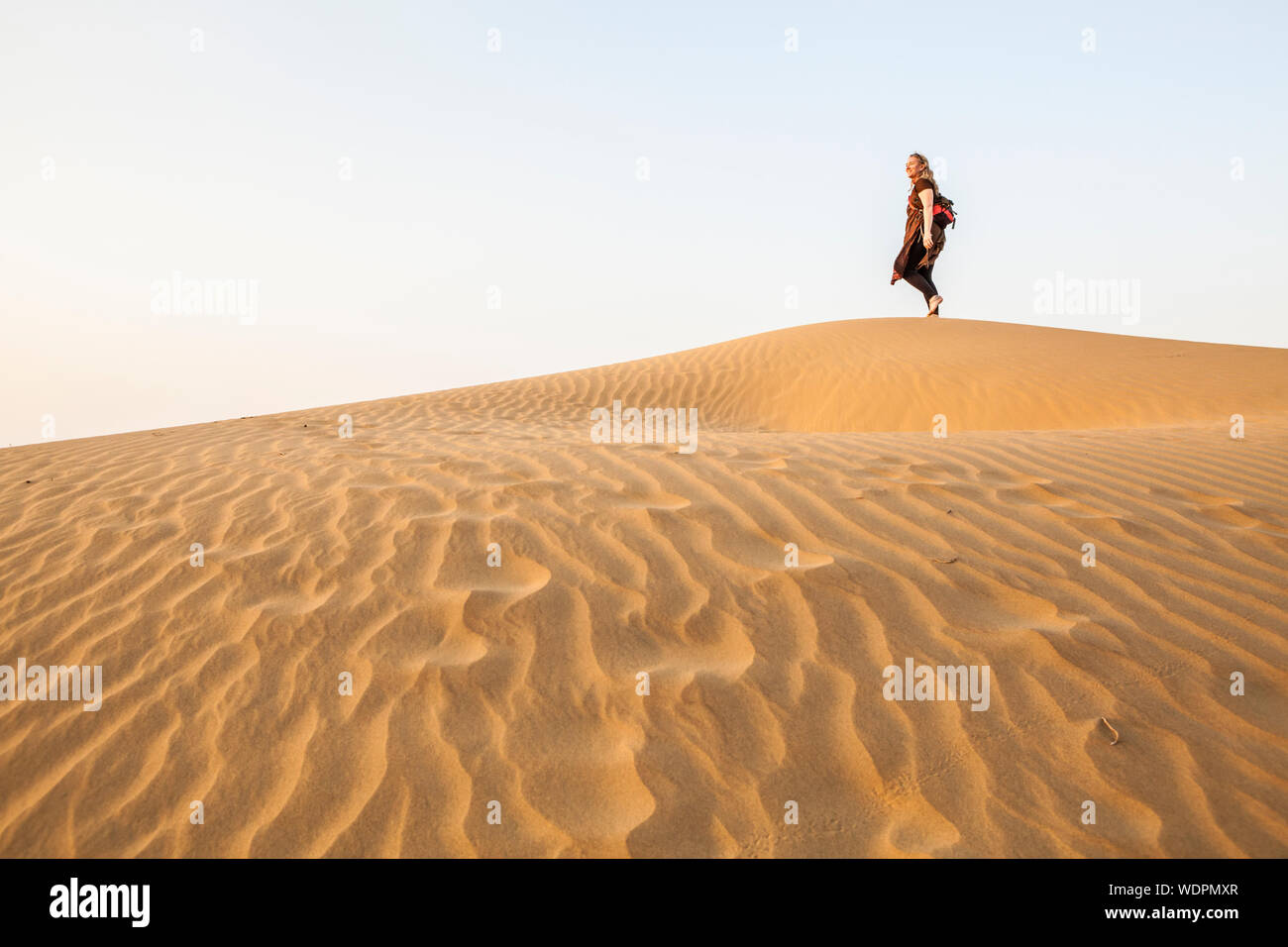 Una mujer en la cima de una duna de arena en el desierto de Thar, Rajasthan, India. Foto de stock