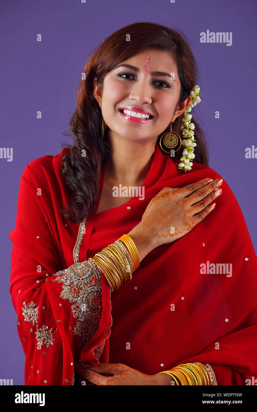 Retrato de hermosa mujer india en Rojo Sari contra fondo púrpura Foto de stock
