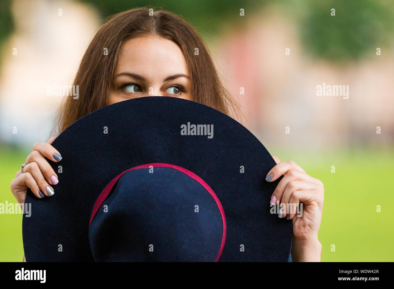Mujer mirando hacia los lados mientras cubrían el rostro con sombrero al aire libre Foto de stock