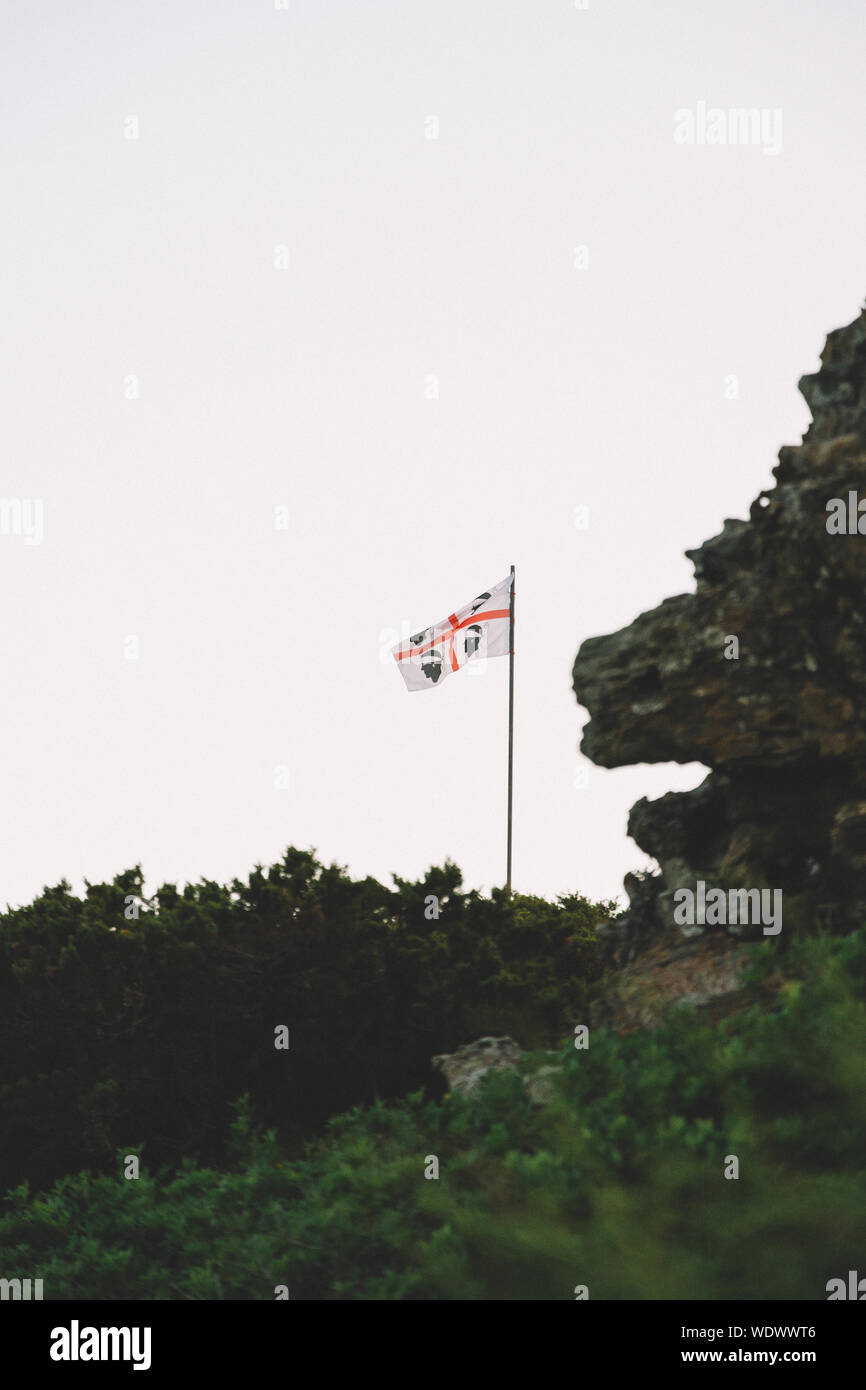 Vista de ángulo bajo bandera de Cerdeña en la montaña contra el cielo claro Foto de stock