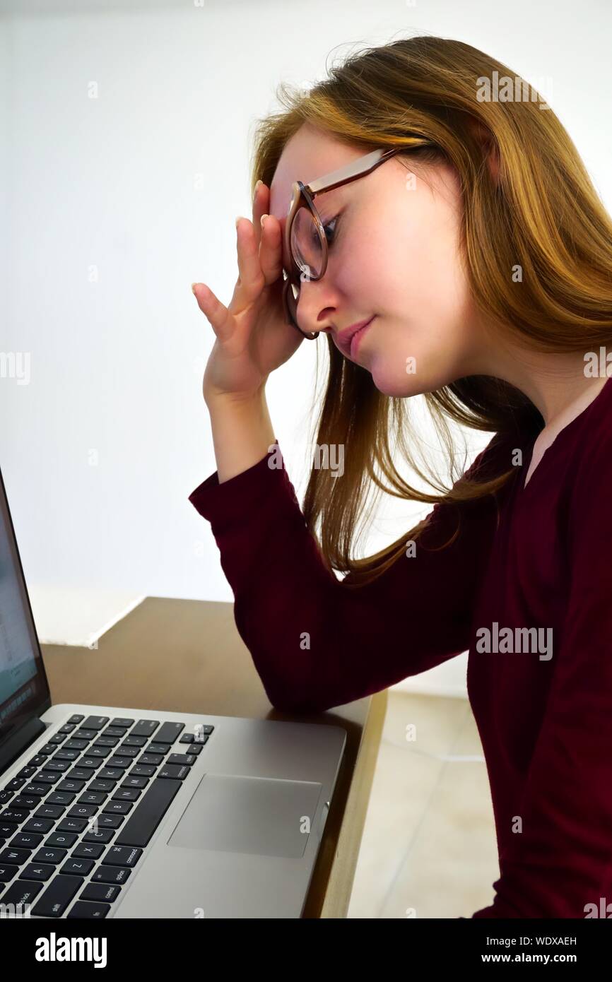 Close-up de estresante Mujer sentada con Digital portátil en la mesa contra la pared Foto de stock