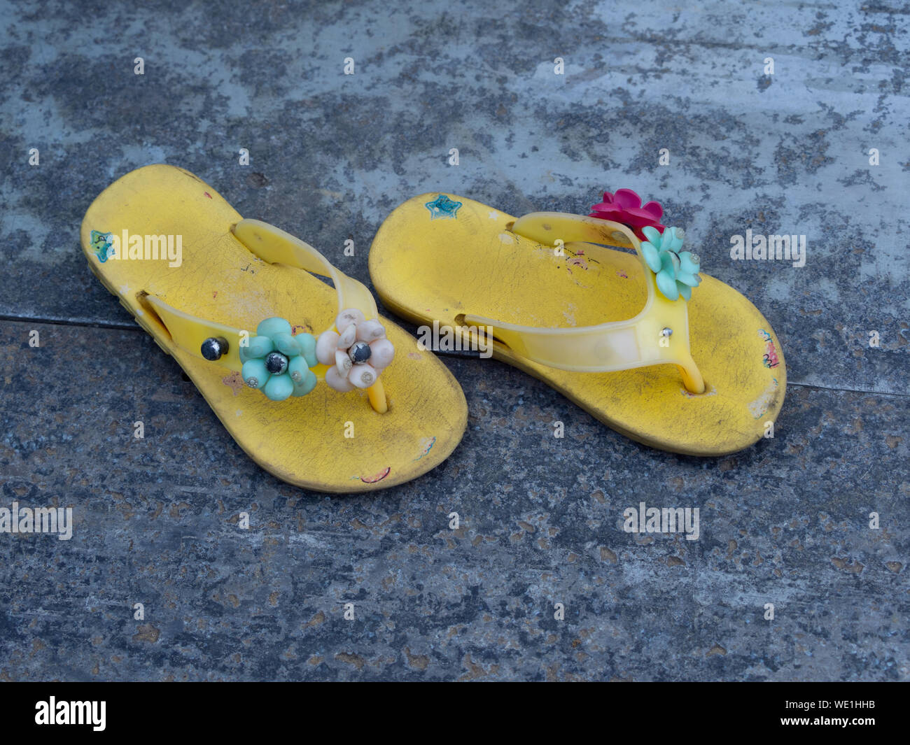 Desgastada amarillo del niño sandalias decoradas con flores de fotografiado arriba Fotografía de stock - Alamy