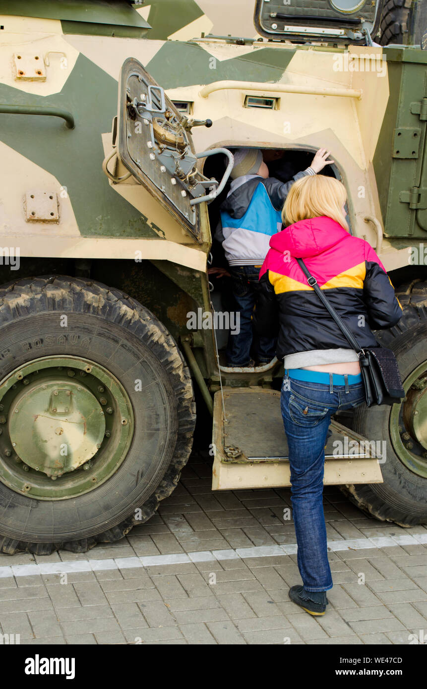 Vista trasera de la madre con su hijo Mirando vehículo militar Foto de stock