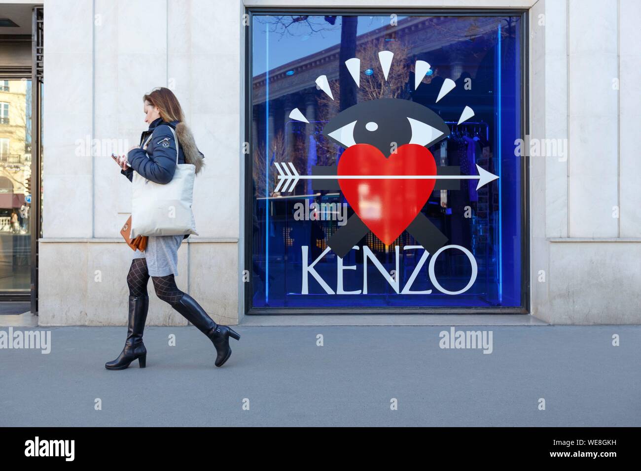 Francia, Paris, mujer caminando por el cristal delantero de Kenzo shop en la Place de la Madeleine. Foto de stock