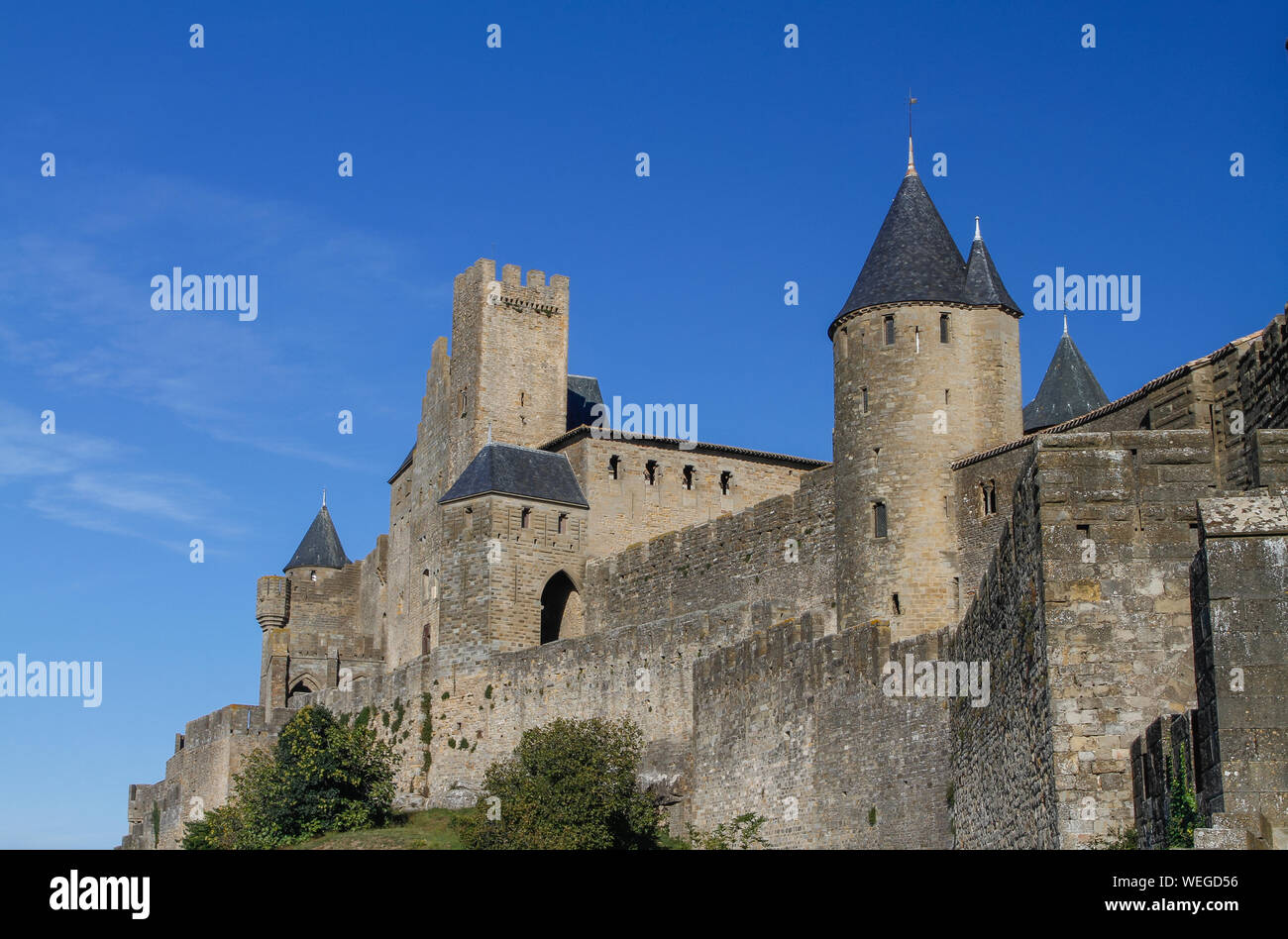 Carcassonne, antigua ciudad fortificada en la cima de una colina en Languedoc-Rosellón en el río Aude, Francia, Europa. Muralla exterior con paredes de cielo azul Foto de stock