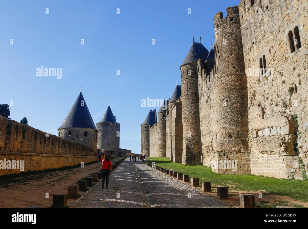 Turistas y vendedor de globos paseos entre rampart murallas de Carcassonne histórica fortaleza de piedra en día soleado con el cielo azul. Francia, Europa Foto de stock
