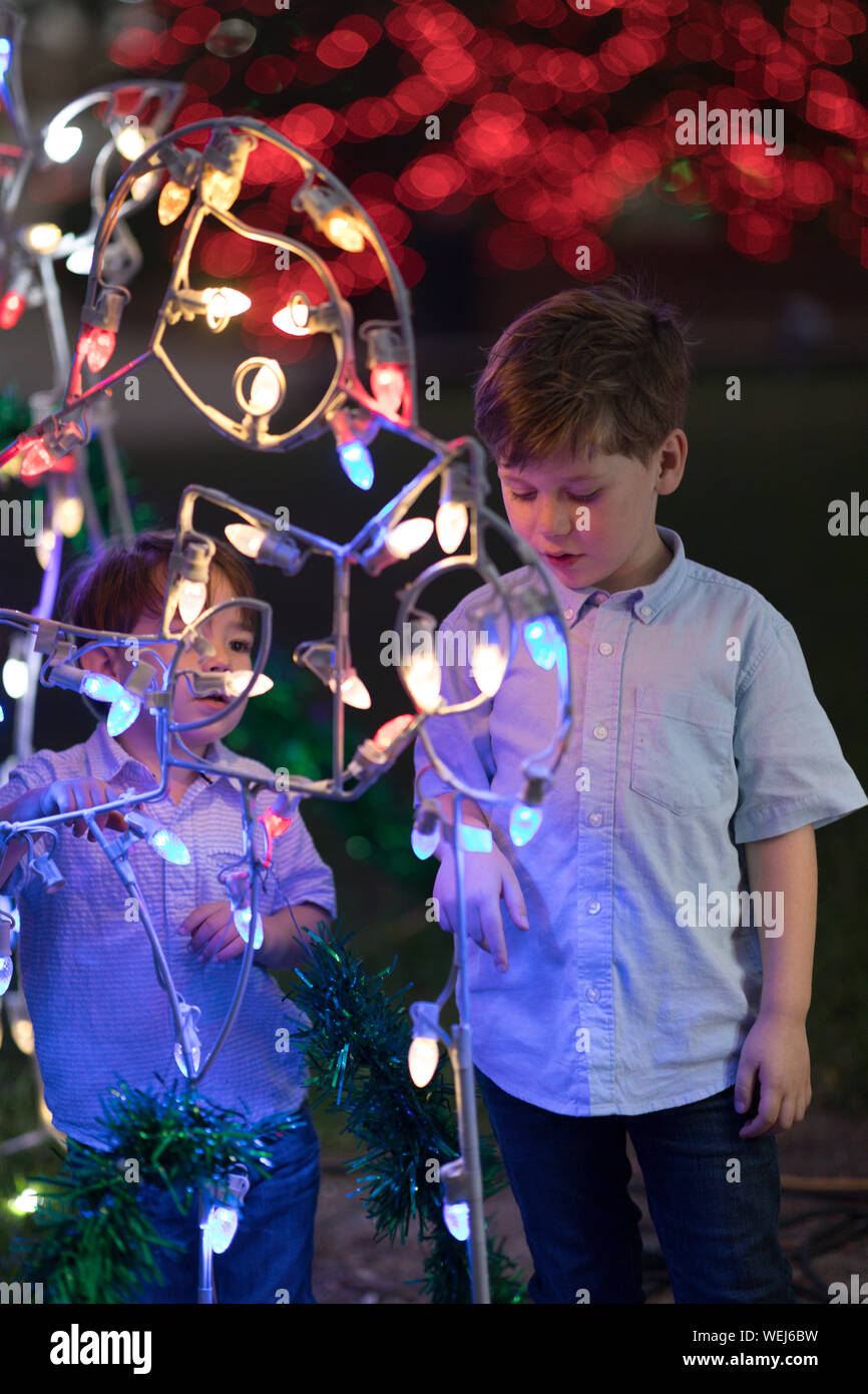 Dos hermanos, de 3 y 5 mirando las luces de Navidad en una feria de atracciones en la noche Foto de stock