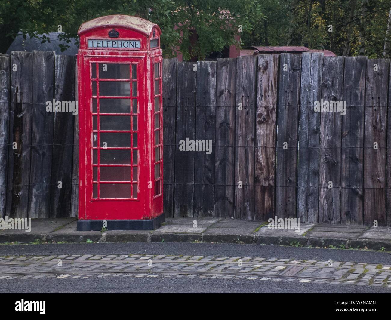 Abandonó la cabina de teléfono inglesa tradicional en la Vereda Contra la pared de madera Foto de stock