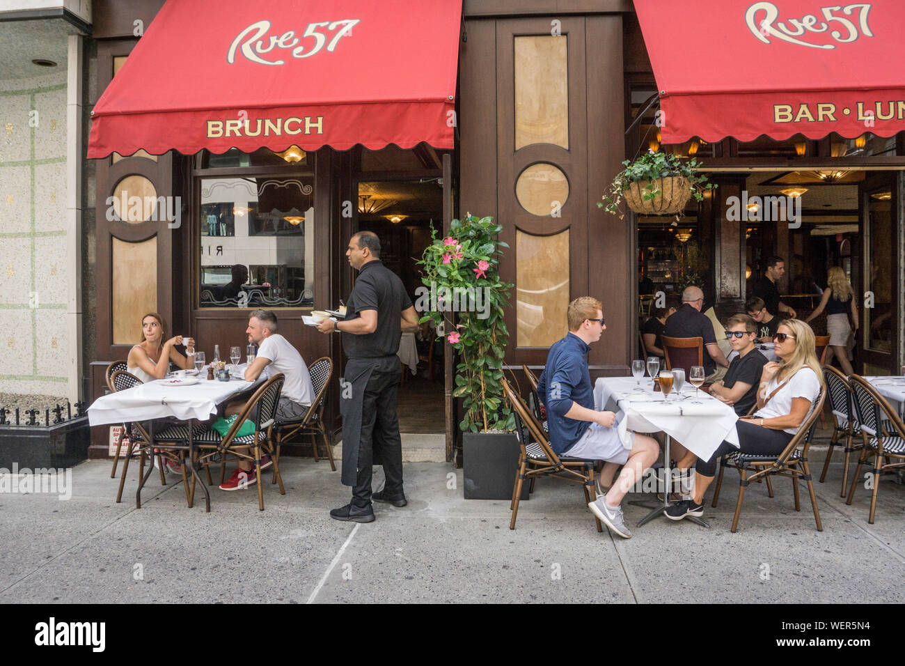 Los turistas relajarse con almuerzo en restaurante acera de la calle 57 en West 57th street una de las principales arterias de midtown Manhattan bueno para personas wathing Foto de stock