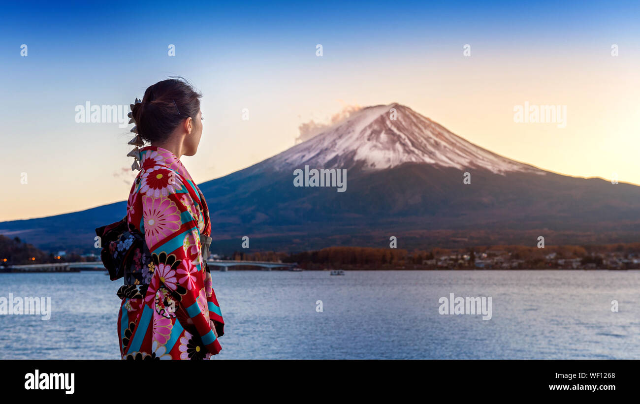 Vista lateral de la mujer en kimono de pie contra el monte Fuji durante el invierno Foto de stock